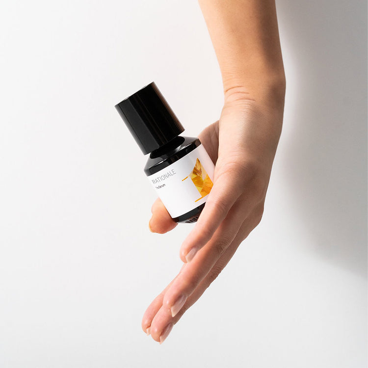 Hand holds a dark pump bottle, RATIONALE The Mask