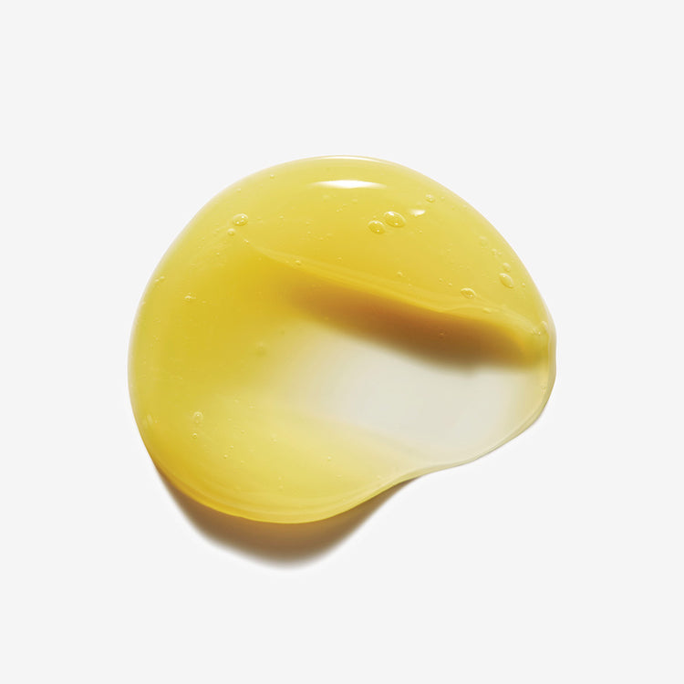 A round, smooth drop of pale yellow liquid on a surface
